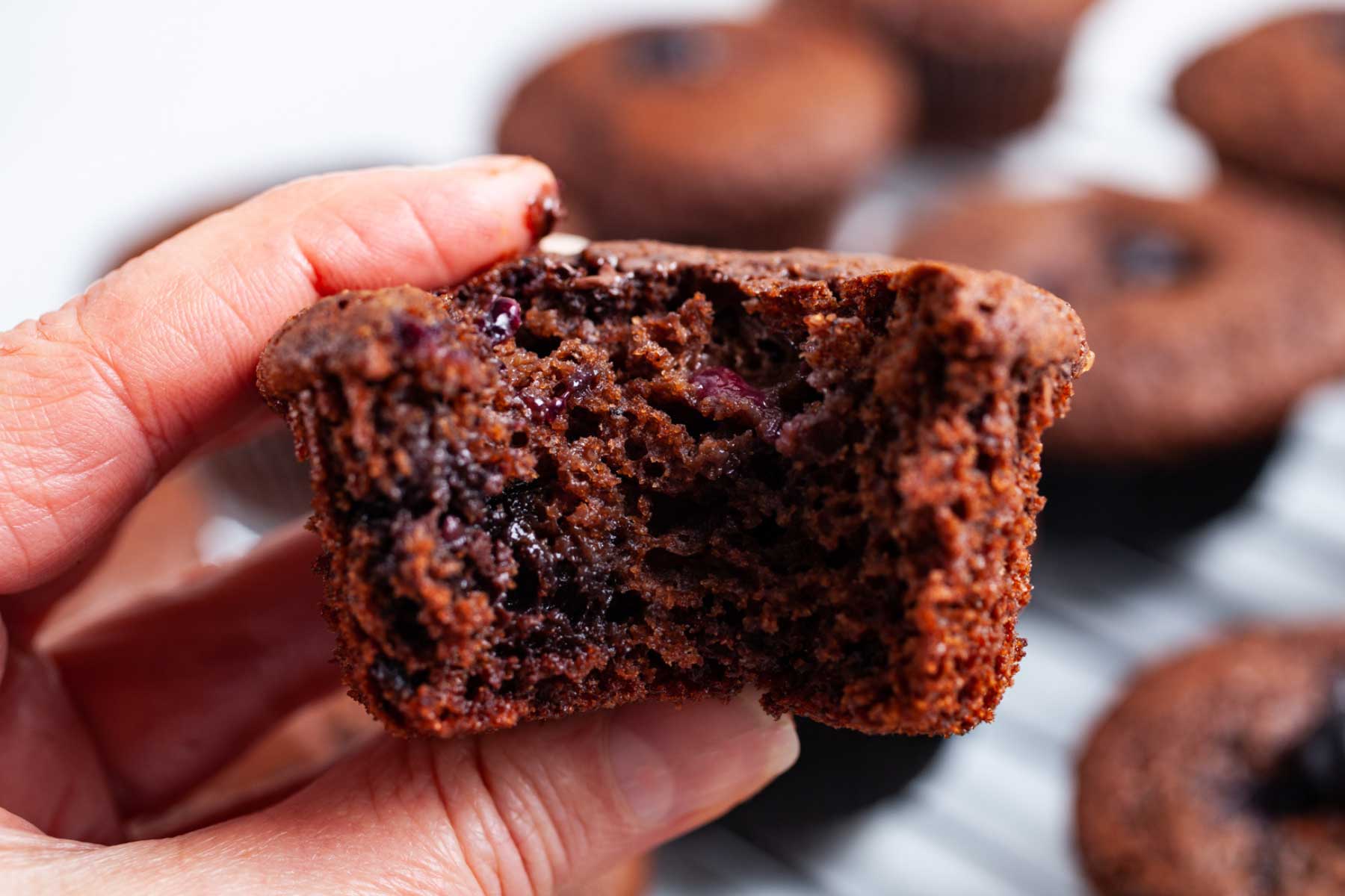 A bite taken out of a chocolate berry muffin.