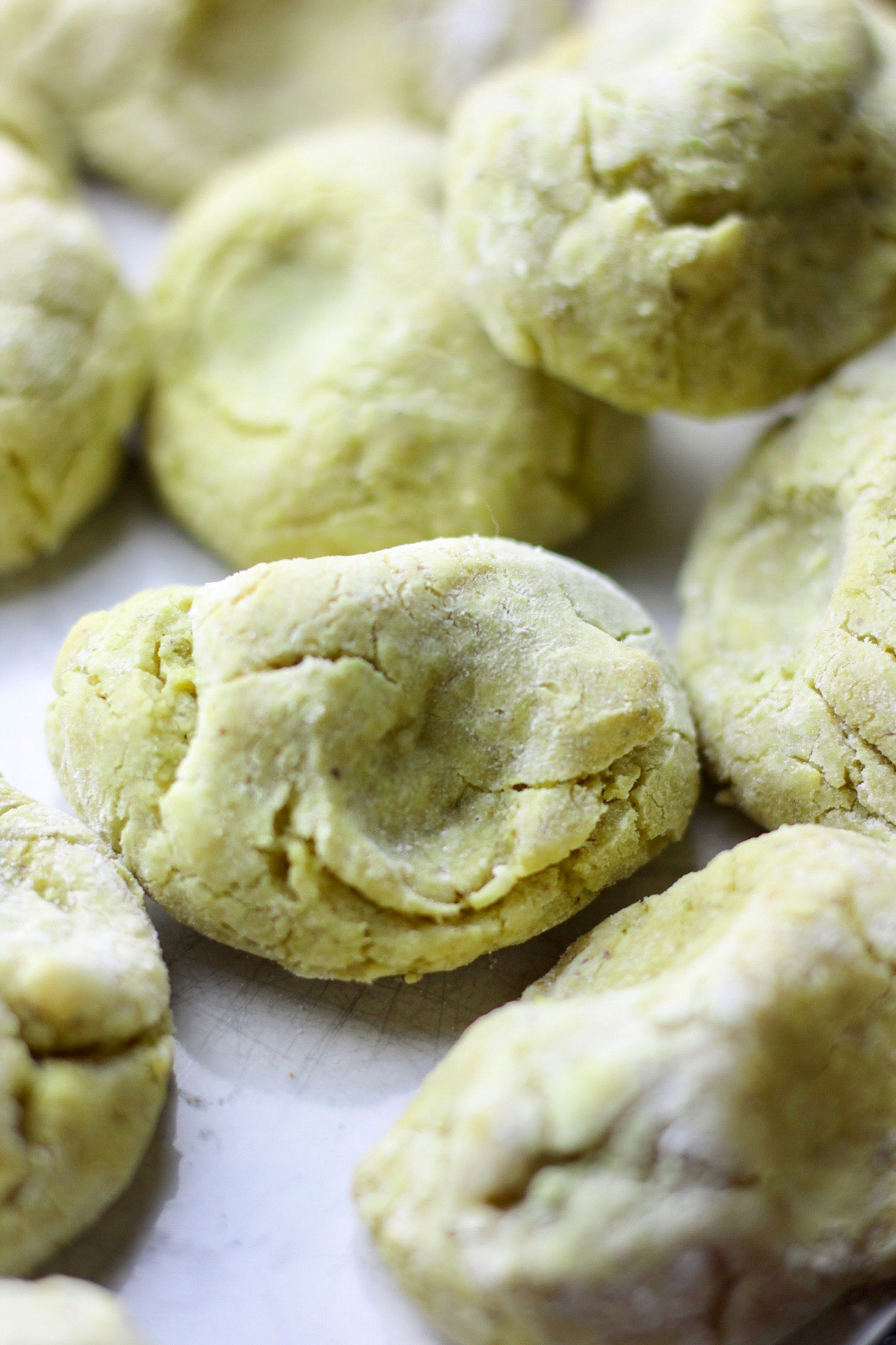 Raw dough of pistachio cookies laid out on a sheet.