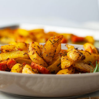 Oven-baked Potatoes with Jamaican Curry and Caraway Fruits in a plate
