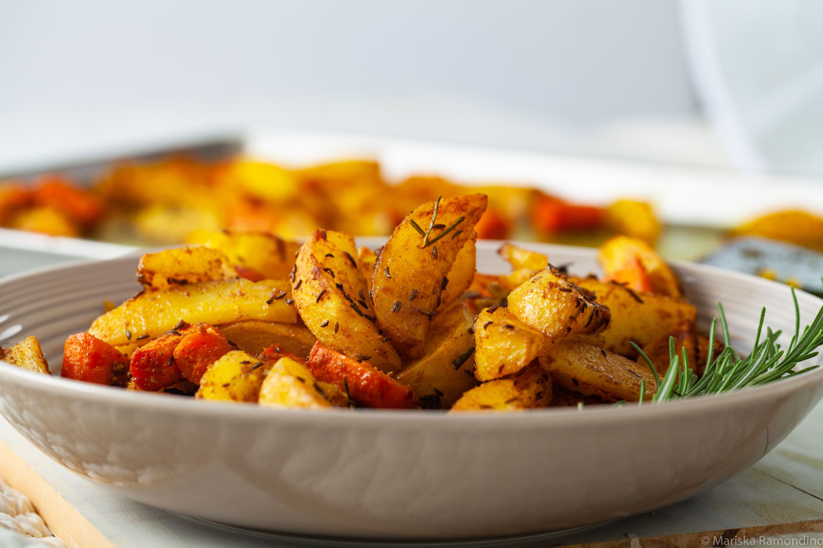 Oven-baked Potatoes with Jamaican Curry and Caraway Fruits in a plate