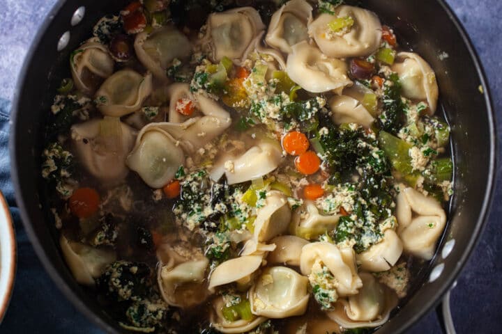 A large pot filled with Italian Straciatella soup with Tortellini.