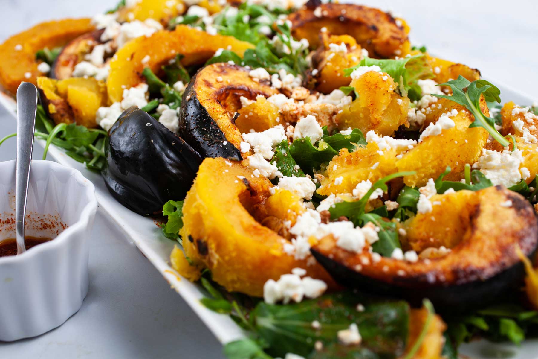 Large acorn squash salad with dressing on a serving plate.