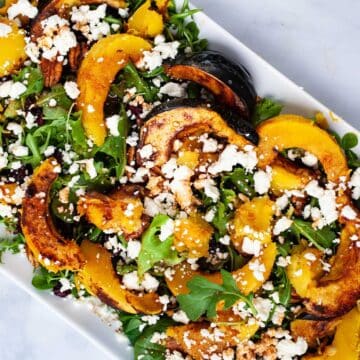Large acorn squash salad with dressing on a serving plate.