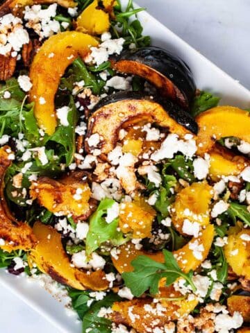 Large acorn squash salad with dressing on a serving plate.