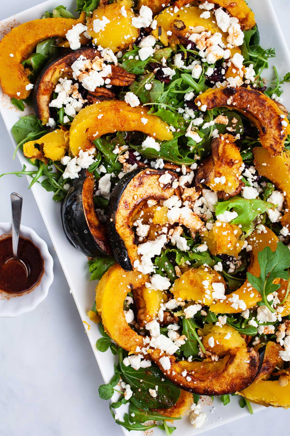 Large acorn squash salad with dressing on a serving plate.
