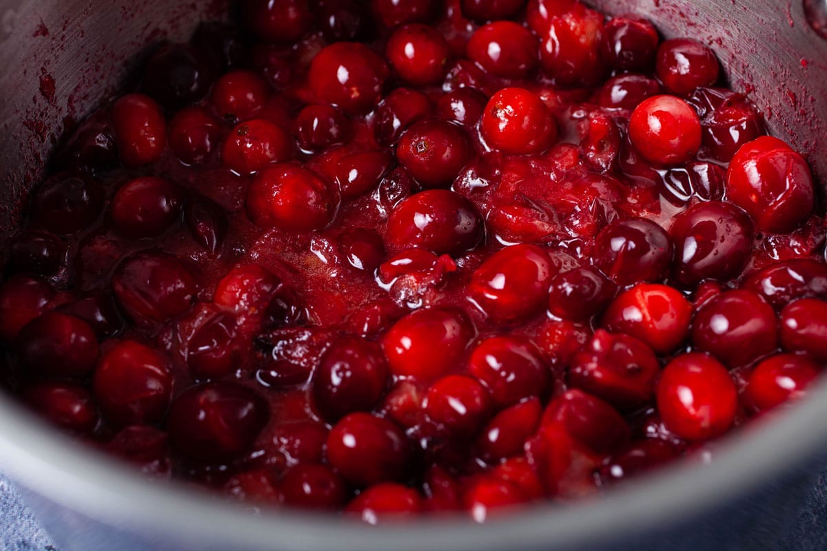Half popped fresh cranberries in a small pan.