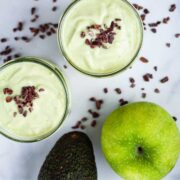 Green apple avocado smoothies garnished with chocolate bits.