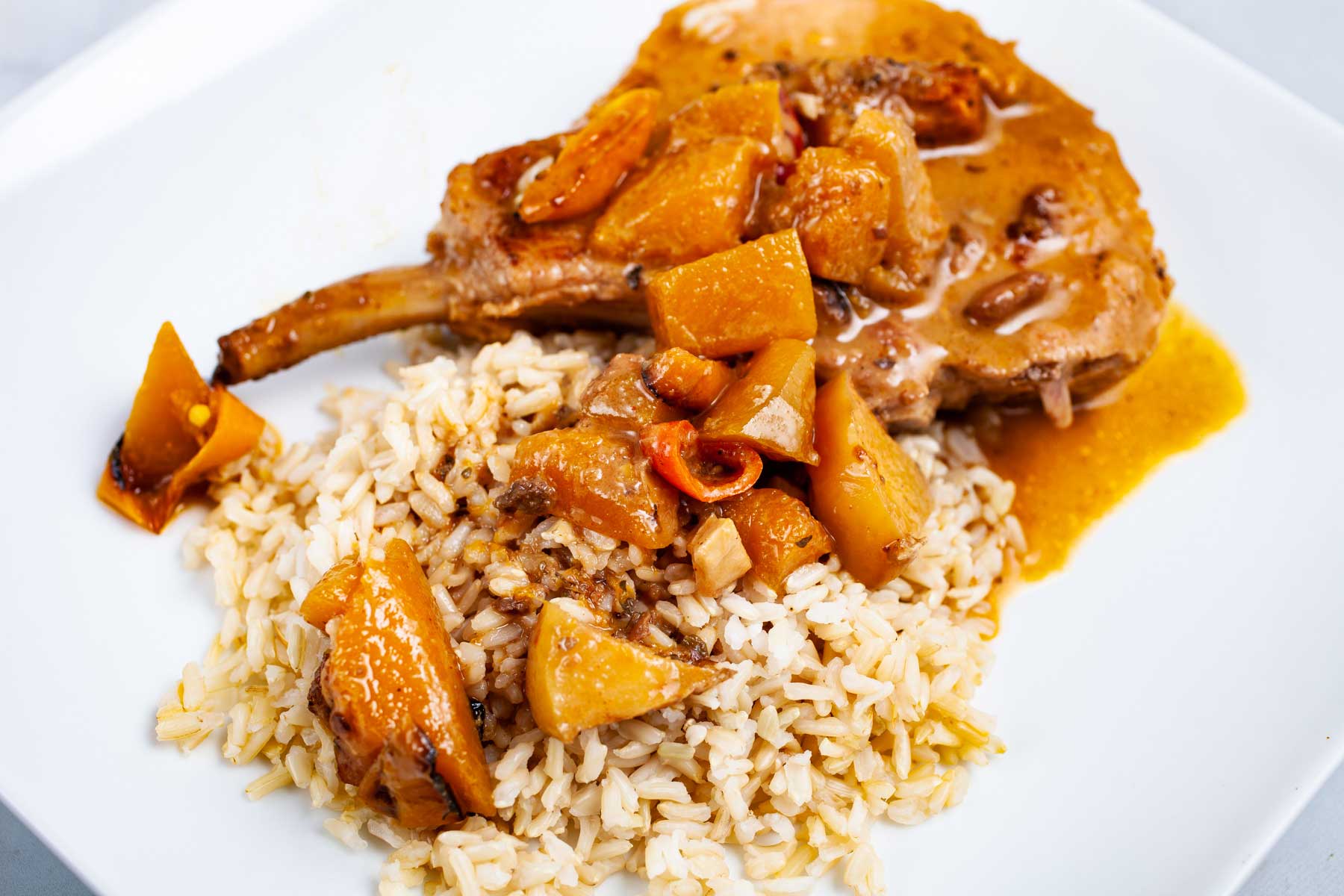 Bone in pork chop with cooked apples and juices served over a bed of rice.