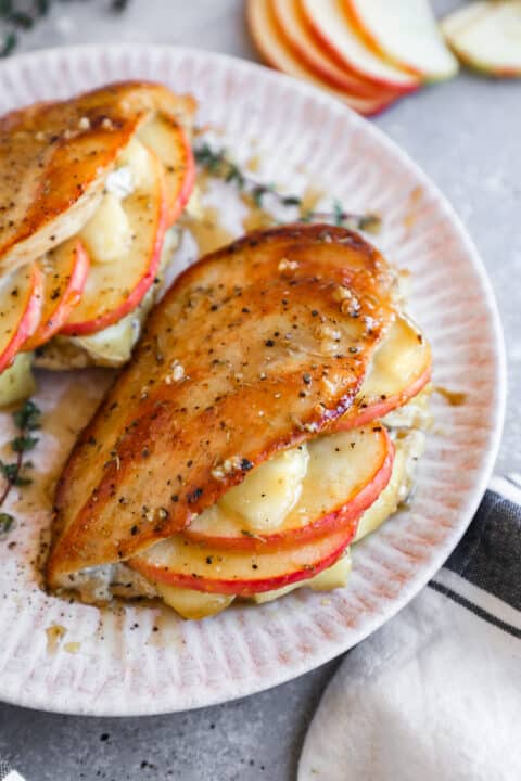 an up close shot of a chicken breast stuffed with cheese and thin slices of apple with the skin on.