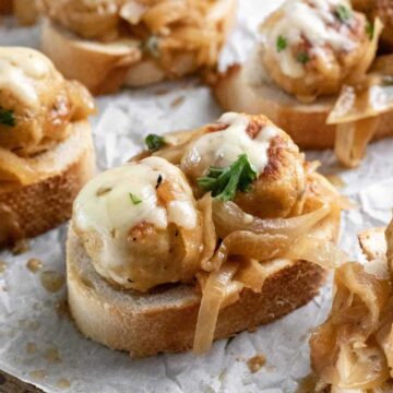 Meatballs topped with caramelized onions and served on sliced baguette as an appetizer.