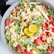 Creamy arugula and cabbage salad with sweet mini tomatoes and pickles served on a plate.