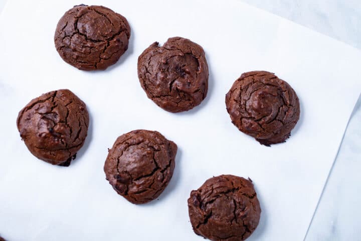 Soft brown baked cookies displayed on parchment paper.