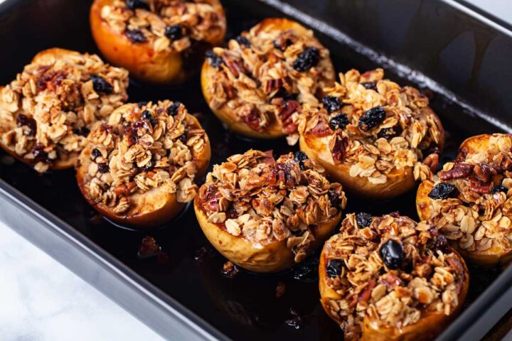 A baking dish containing stuffed and syrupy apples.