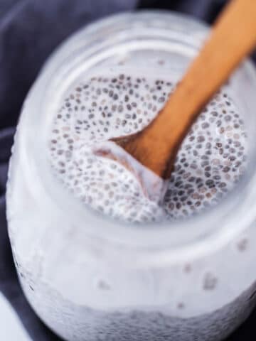 A wooden spoon resting in a jar with chia seed pudding.