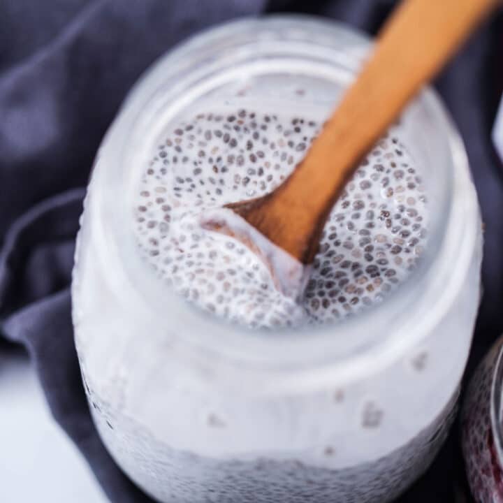 A wooden spoon resting in a jar with chia seed pudding.