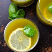 Green Basil lemonade drinks garnished with lemon wedges and fresh basil leaves.