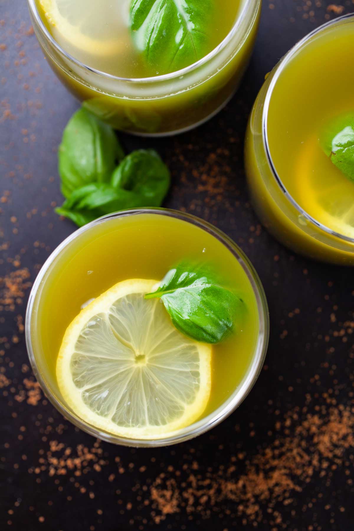 Green Basil lemonade drinks garnished with lemon wedges and fresh basil leaves.
