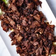 A large serving plate with shredded beef tacos chuck roast.