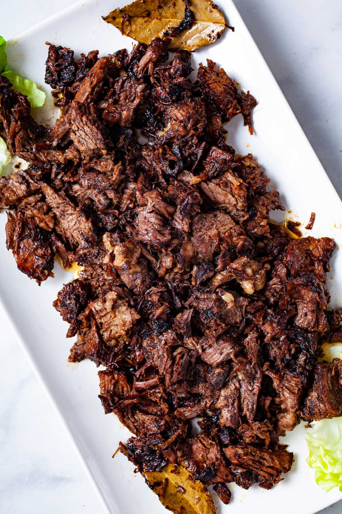 A large serving plate with shredded beef tacos chuck roast.