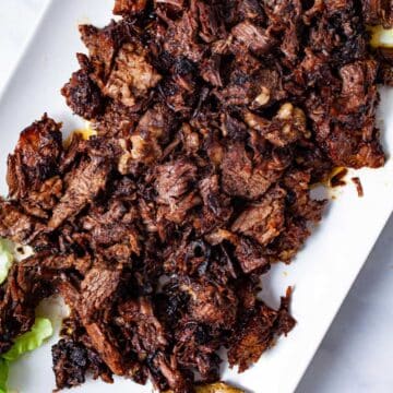 A large serving plate with shredded beef tacos chuck roast.