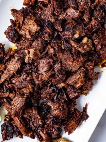 A large serving plate with shredded beef tacos chuck roast.