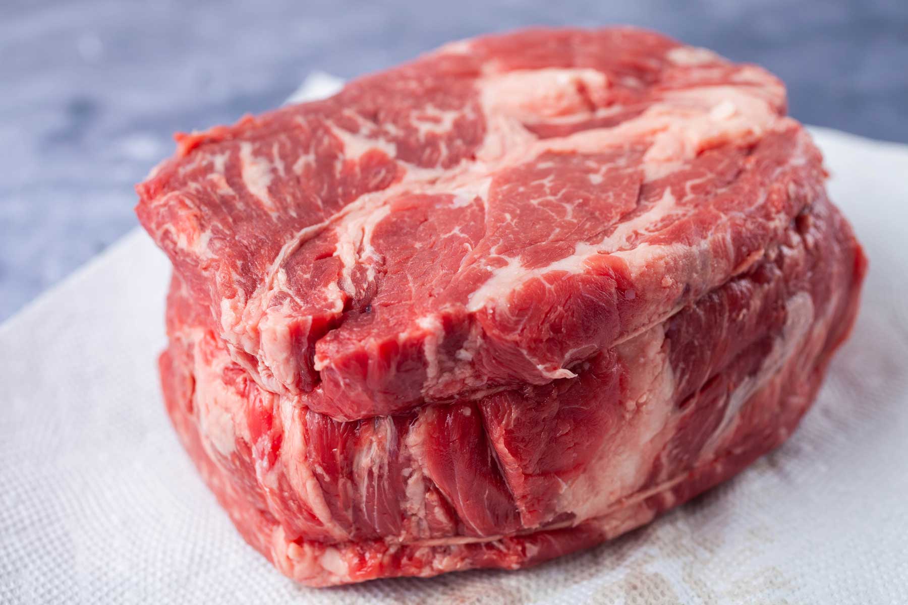 A large piece of raw beef chuck resting on paper towel.
