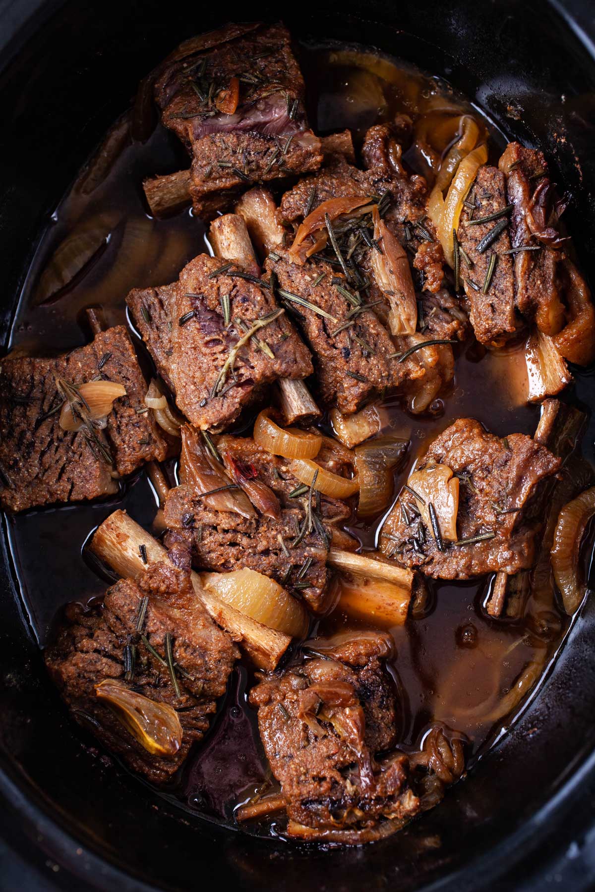 A slow cooker containing deliciously spiced fall of the bone ribs.