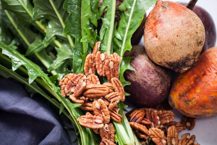 Raw dandelion greens, pecans, and red and golden raw beets.