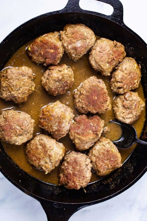 Meatballs in sauce in a cast-iron skillet.