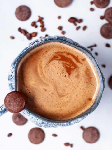 Bone broth hot chocolate in a cup surrounded by chocolate wafers.