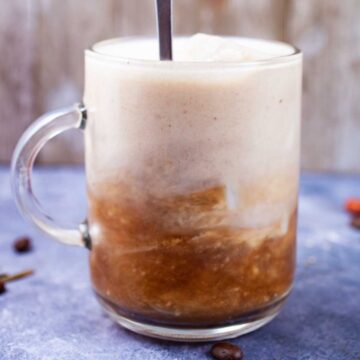 A spoon being stirred into a cold brew latte.