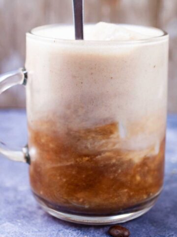 A spoon being stirred into a cold brew latte.