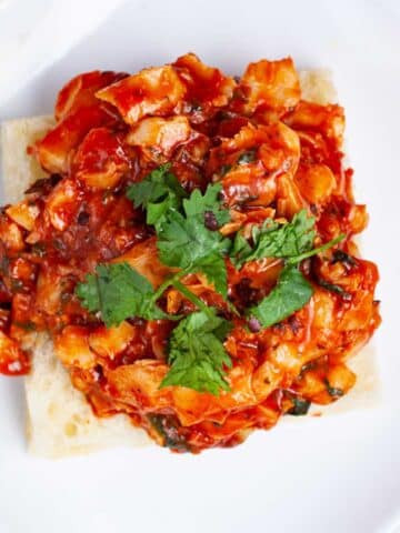 An open Focaccia Sandwich with pan-fried cod fish in red tomato sauce.