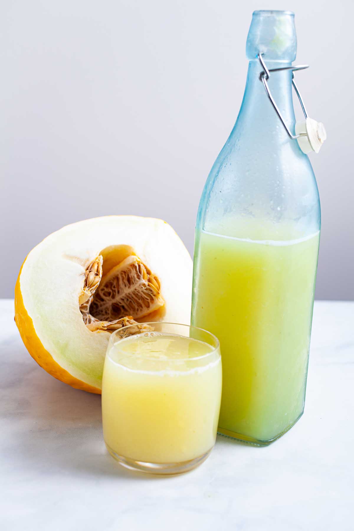 Honeydew lemonade in a glass and bottle next to each other.