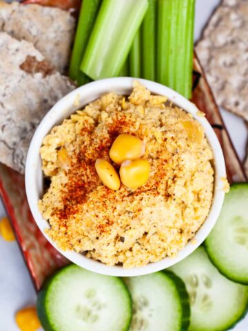 Keto hummus with lupini beans surrounded with fresh veggies and crackers.