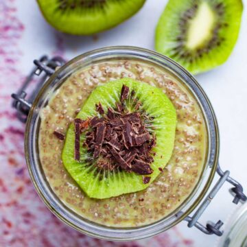 A cup filled with kiwi chia pudding topped with a slice of fresh kiwi fruit and shaved chocolate.