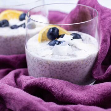 Two cups filled with lemon chia pudding topped with blueberries.