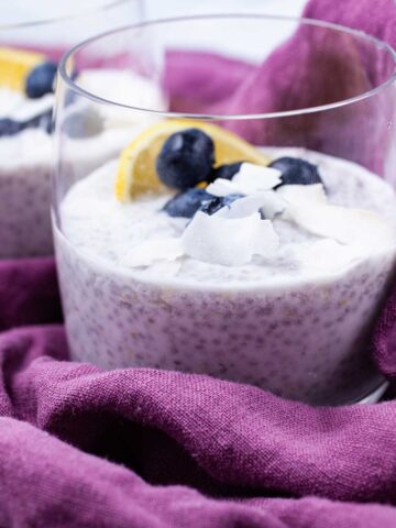 Two cups filled with lemon chia pudding topped with blueberries.