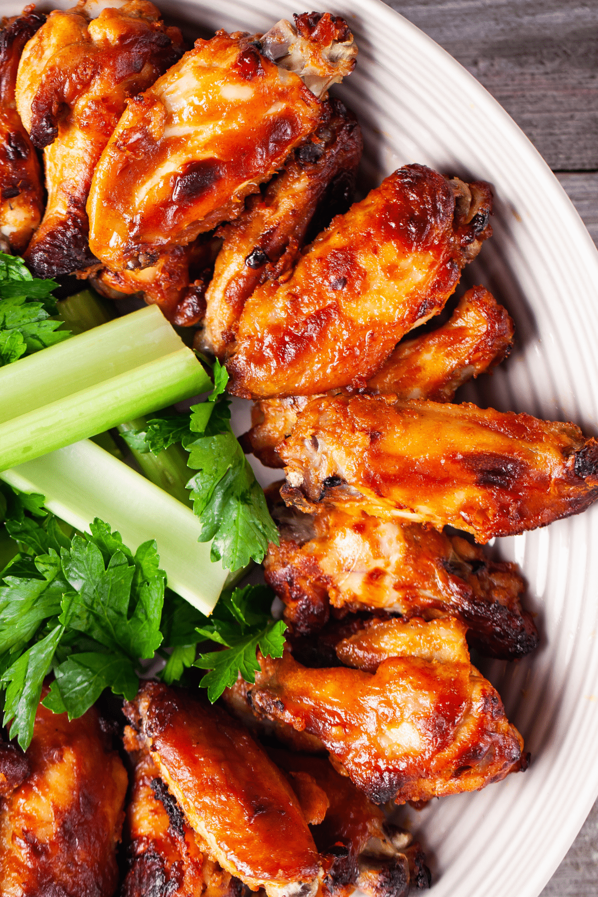 Marinated chicken wings presented on a plate with celery pieces.