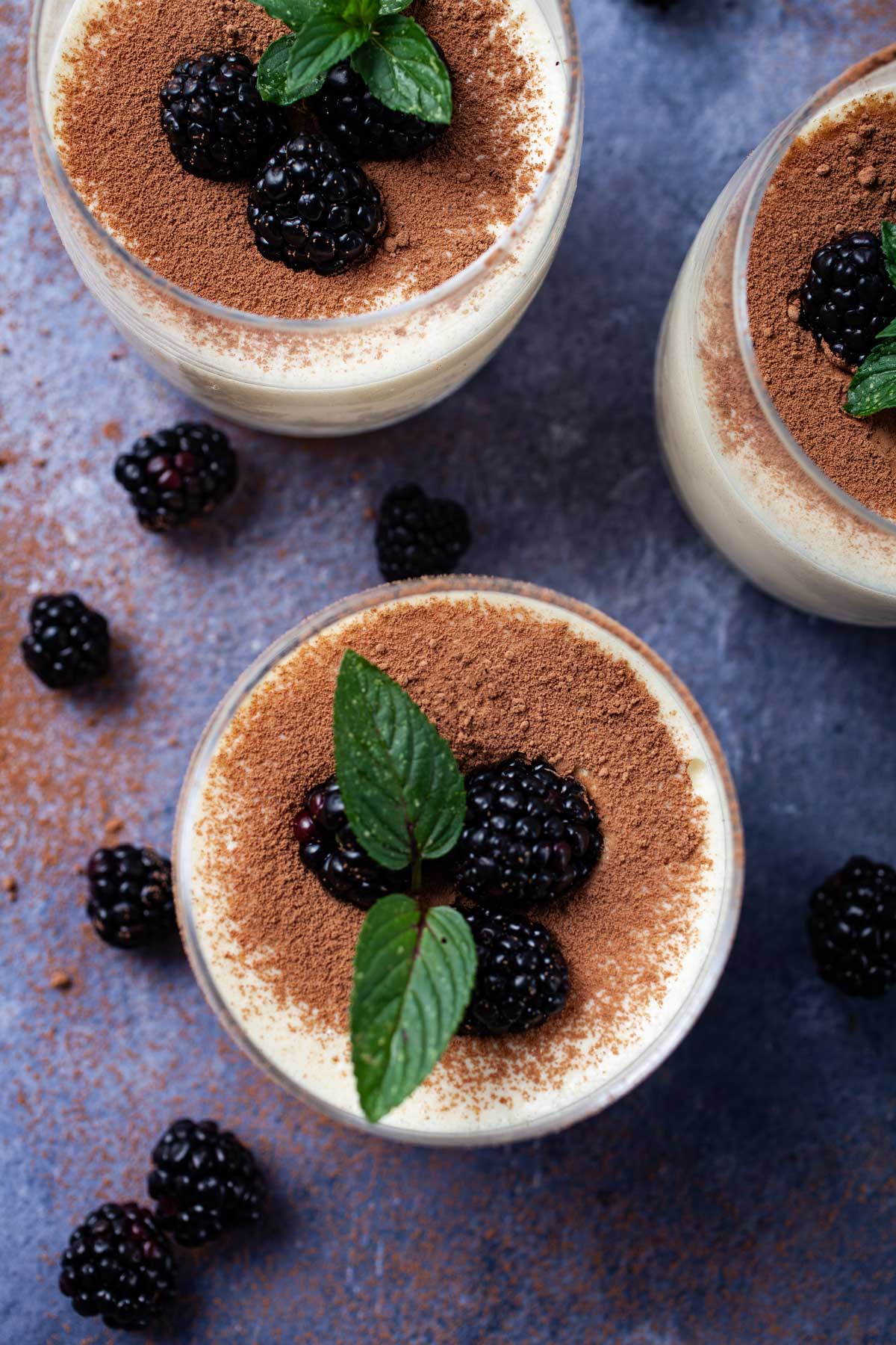 Mascarpone mousse served in cups and garnished with cacao powder and berries.
