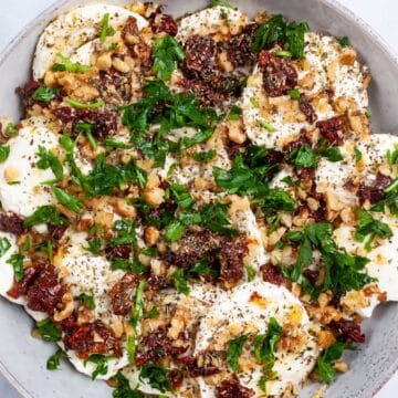 A large mozzarella and dried tomatoes appetizer plate on a table.