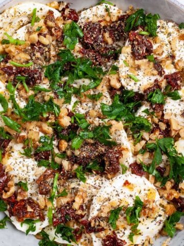 A large mozzarella and dried tomatoes appetizer plate on a table.