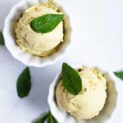 Two small bowls with pineapple avocado ice cream and topped with fresh mint leaves.