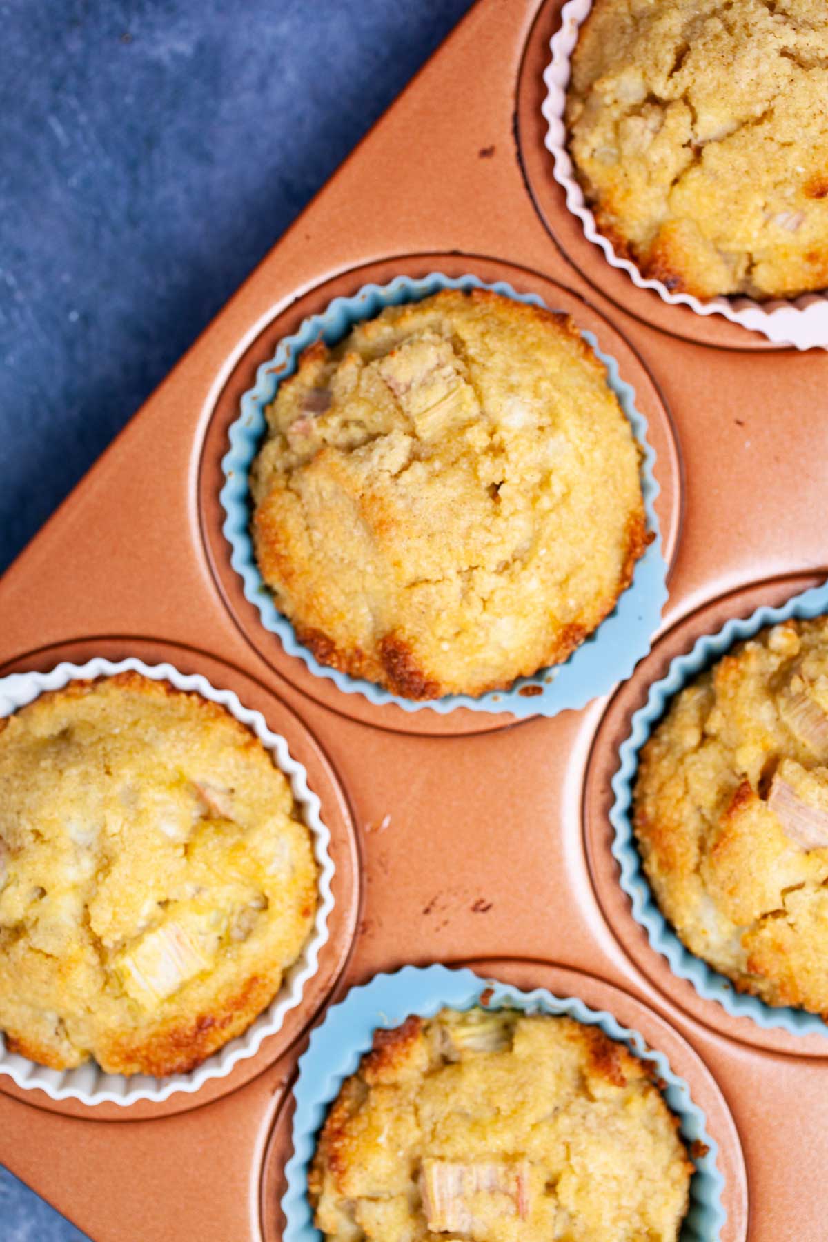 Golden brown rhubarb muffins in a muffin tin.