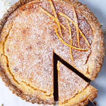 A piece lifted and taken out of a large ricotta pie.