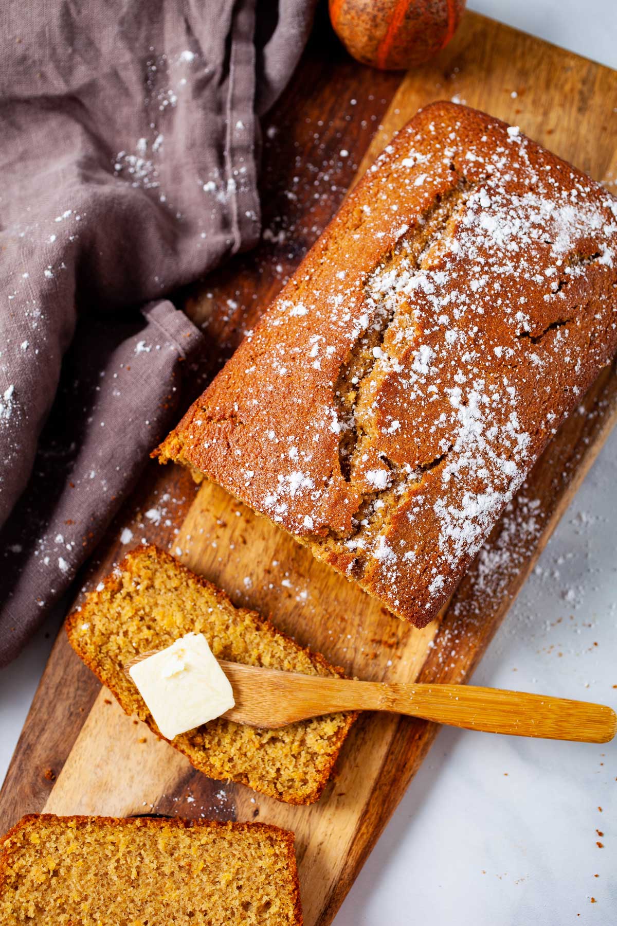 A sliced spelt cake loaf topped with butter.