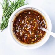 A spoon resting in a ramekin filled with spiced apricot jam.