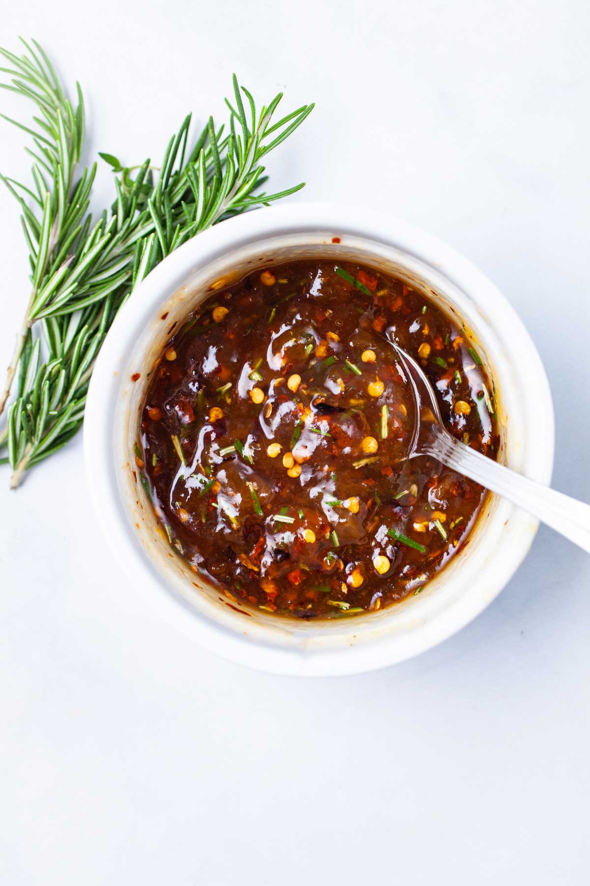 A spoon resting in a ramekin filled with spiced apricot jam.