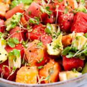 A watermelon fruit salad with papaya and avocado and crunchy seeds served in a bowl.