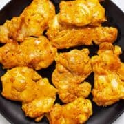 Baked boneless skinless chicken thighs on a plate.